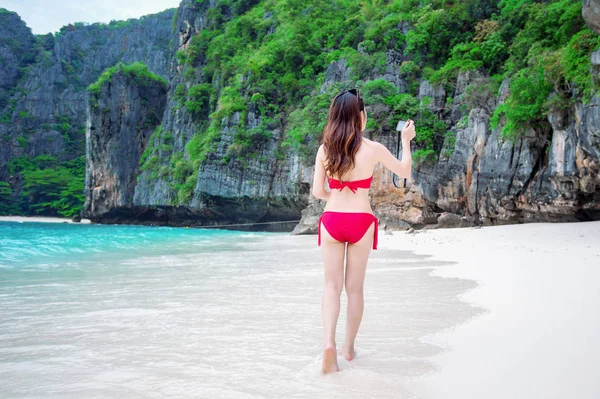 Menina sexy vestindo um biquíni vermelho e tirar uma foto na praia . — Fotografia de Stock