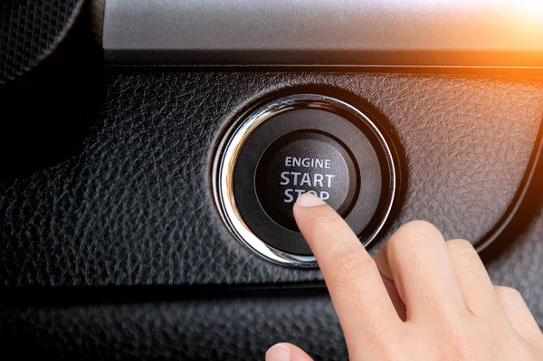 Fechar o dedo pressionando o botão do motor de partida / parada em um carro . Fotos De Bancos De Imagens