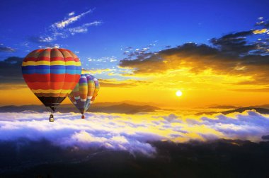 Güneş doğarken tarafından sabah sis kaplı dağ üzerinde uçan renkli sıcak hava balonları.