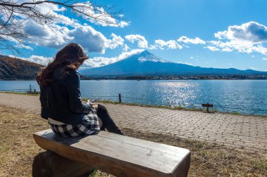 Gölde kawaguchiko, Japonya bir bankta oturan kadın. Fuji dağlarının görünümü.