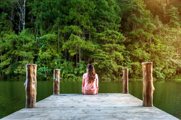 Menina sentada sozinha em uma ponte de madeira no lago. Pang Ung, Tailândia . — Fotografia de Stock