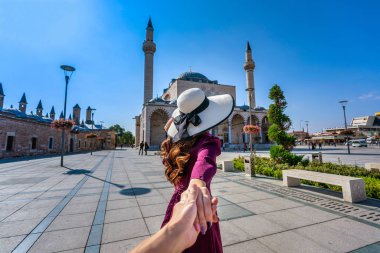 Kadın turistler erkeğin elini tutuyor ve Türkiye 'nin Konya kentindeki camiye götürüyor.