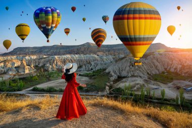 Kapadokya, Türkiye 'de ayakta duran ve sıcak hava balonları arayan güzel kız.