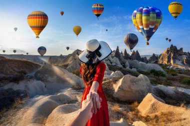 Kadın turistler erkeğin elini tutuyor ve Kapadokya, Türkiye 'de sıcak hava balonlarına götürüyor.