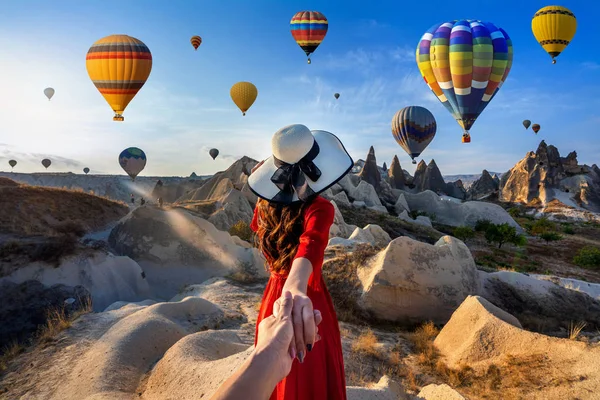 Touristes femmes tenant la main de l'homme et le menant à des montgolfières en Cappadoce, Turquie . — Photo