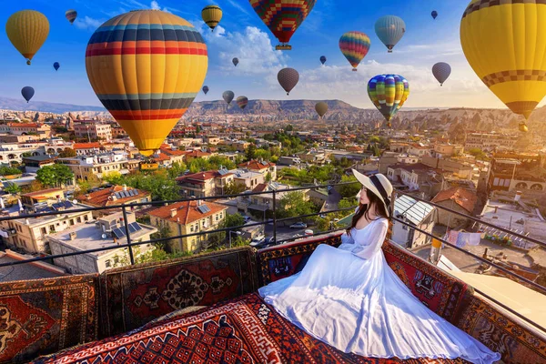 Hermosa chica sentada en el hotel y mirando globos de aire caliente en Capadocia, Turquía . — Foto de Stock