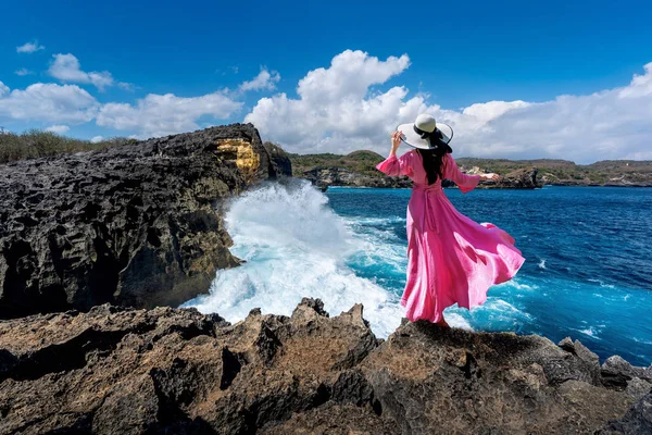 美しい女の子が岩の上に立っていますエンジェルズ・ビラボン近くヌサペニダ島の壊れたビーチ,インドネシアのバリ. — ストック写真