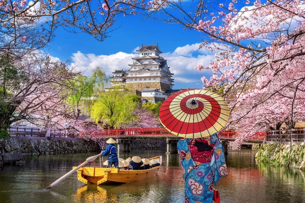 Mujer asiática usando kimono tradicional japonés mirando flores de cerezo y castillo en Himeji, Japón . — Foto de Stock