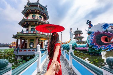 Kadın turistler erkeğin elini tutuyor ve onu Kaohsiung 'un Tayvan' daki ünlü turistik mekanına götürüyor..
