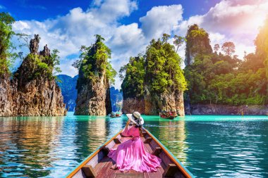 Güzel kız teknede oturan ve Khao Sok Milli Parkı Ratchaprapha Barajı dağlara bakıyor, Surat Thani Eyaleti, Tayland.