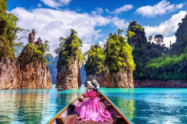 Güzel kız teknede oturan ve Khao Sok Milli Parkı Ratchaprapha Barajı dağlara bakıyor, Surat Thani Eyaleti, Tayland.
