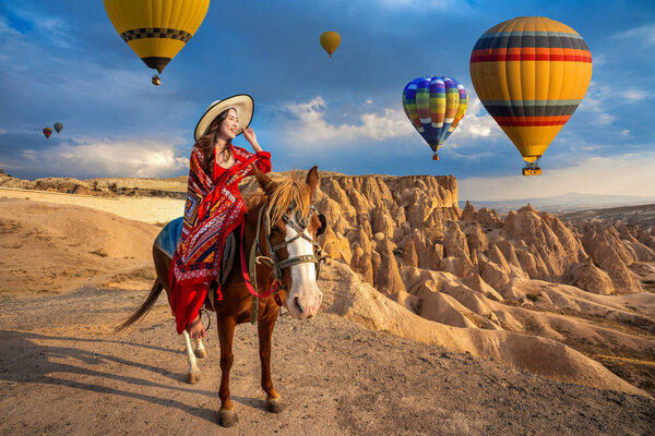 Туристы любят ездить верхом на лошадях и смотреть на воздушные шары в Каппадокии, Турция
