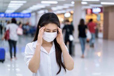 Koronavirüsten korunmak için baş ağrısı çeken bir kadın tıbbi maske takıyor..