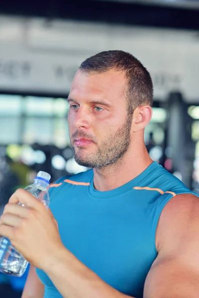 man drinking water at gym