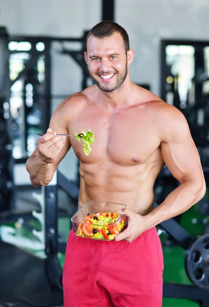 Sportlicher Mann mit gesundem Salat im Fitnessstudio — Stockfoto