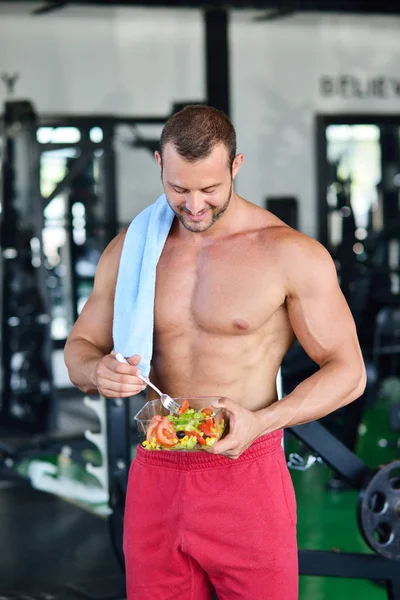 Sportlicher Mann mit gesundem Salat im Fitnessstudio — Stockfoto