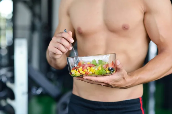 Sportlicher Mann mit gesundem Salat im Fitnessstudio — Stockfoto