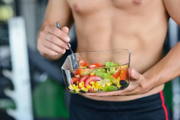 Atletisk man med hälsosam sallad på gym — Stockfoto