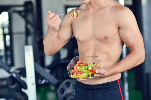 Sportlicher Mann mit gesundem Salat im Fitnessstudio — Stockfoto