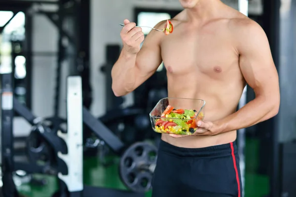 Sportlicher Mann mit gesundem Salat im Fitnessstudio — Stockfoto