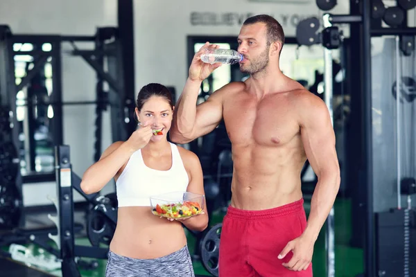 Par av bodybuilders äter på gym — Stockfoto