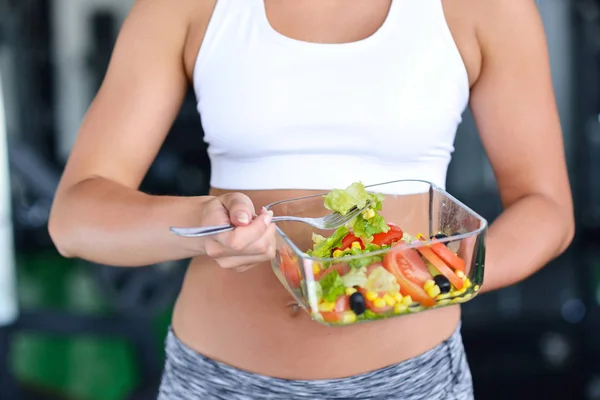 Sportieve vrouw salade eten op sportschool Stockfoto