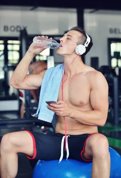 Hombre en ropa deportiva escuchando música en el gimnasio —  Fotos de Stock