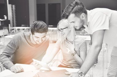 Kitap ve dijital tablet ile kafede oturan ve fotoğraf arıyor öğrenci grubu