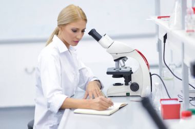 Laboratuarda bir mikroskop kullanarak bir genç bilim adamı portresi