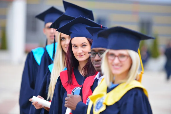 Grupo de graduados universitários multiculturais de pé em uma fileira — Fotografia de Stock