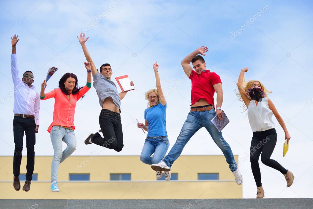 Group of international students holding books outdoors, university building background