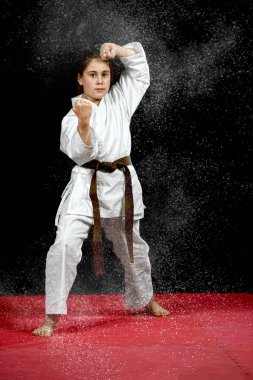 One little girl in white kimono during training karate kata exercises  clipart