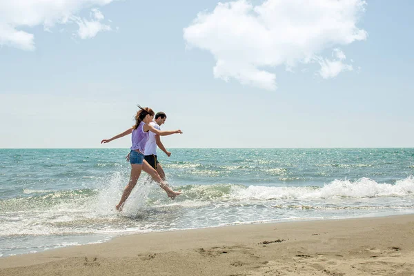 Pareja Joven Divirtiéndose Juntos Mientras Corren Saltan Agua Playa —  Fotos de Stock