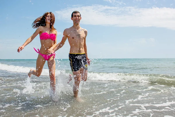 Pareja Joven Divirtiéndose Juntos Mientras Corren Saltan Agua Playa —  Fotos de Stock