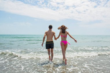 Sahilde birlikte yürüyen genç çiftin arka plan görüntüsü. 