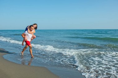  Sahilde sırtında kadın taşıyan bir adam.