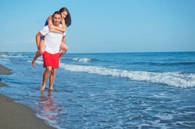  Sahilde sırtında kadın taşıyan bir adam.