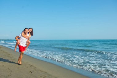  Sahilde sırtında kadın taşıyan bir adam.