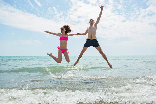 Genç çift sahilde koşup zıplarken birlikte eğleniyor. 