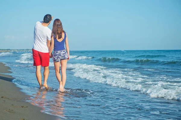 rear view of couple walking by sea shore at daytime
