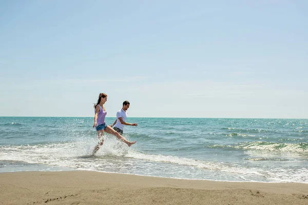 Pareja Joven Divirtiéndose Juntos Mientras Corren Saltan Agua Playa —  Fotos de Stock