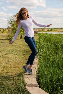 Kızıl saçlı modeli parapetin üzerinde teetering