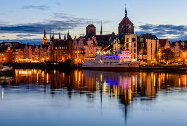 Gdansk, Polonya - 7 Ekim 2019: Polonya turu. Gdansk 'ın gece manzarası. Binaların cepheleri ve motlava nehrinde aydınlatmalı bir gemi.