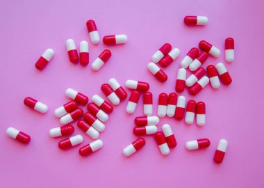 Pembe arka plan üstten görünüm haplarla kırmızı kapsül yığını. Tıp Sağlık eczane Farmakoloji kavramı