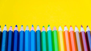 Sarı arka plan üzerinde renkli kalem kümesi 