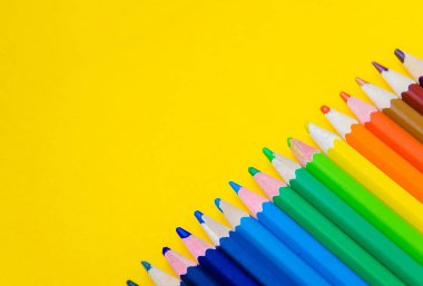 Sarı arka plan üzerinde renkli kalem kümesi 