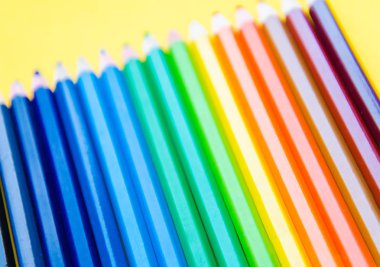 Sarı arka plan üzerinde renkli kalem kümesi 