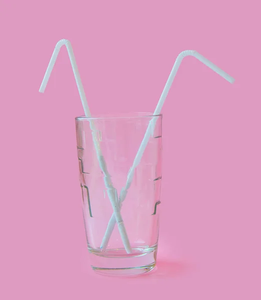 Fresh Juice glass with a straw slice of yellow lemon on a pink background. Fashion pastel summer design style concept