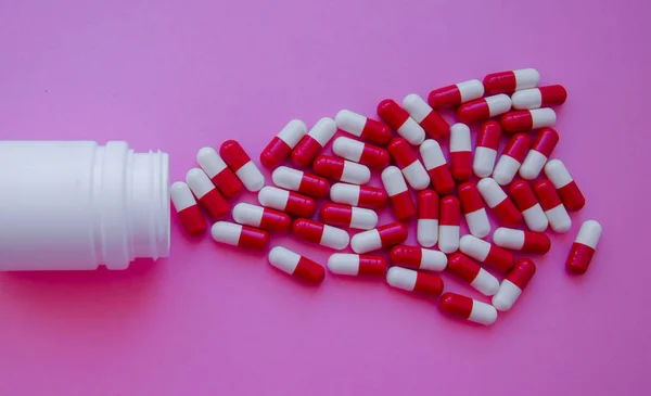 药丸胶囊从药丸瓶中溢出 并被粉红色隔离 具有复制空间的顶部视图 医药药学药理学健康观 — 图库照片
