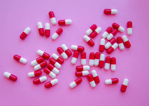 Pile of red capsules of pills on a pink background top view. Medicine Health Pharmacy Pharmacology Concept